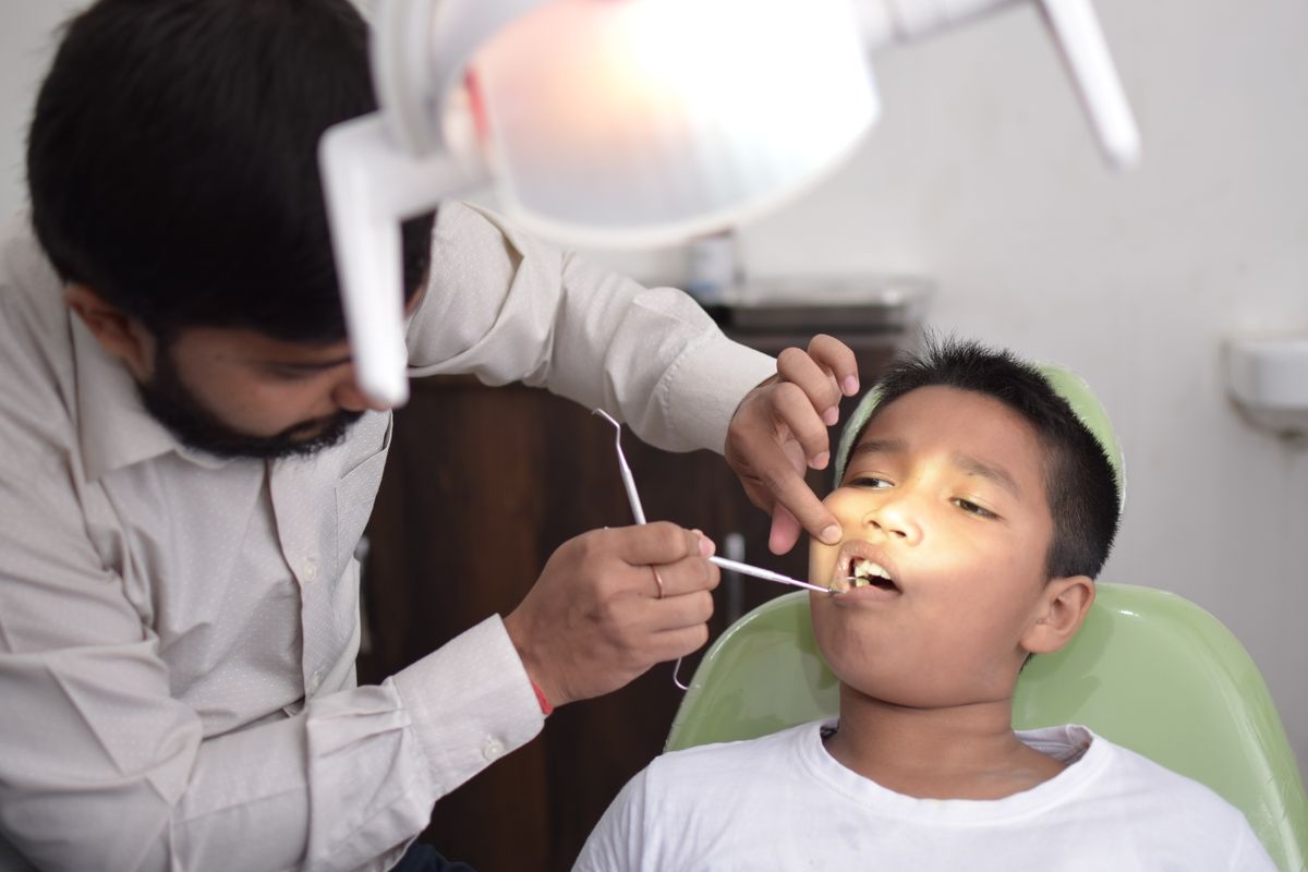 Dentist checking a boy’s back teeth in a dental chair