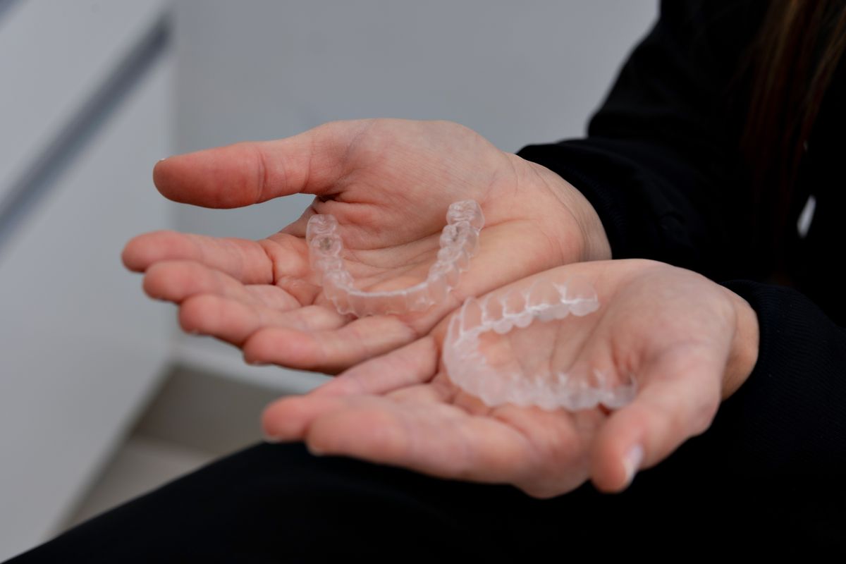Hands holding two clear aligner trays