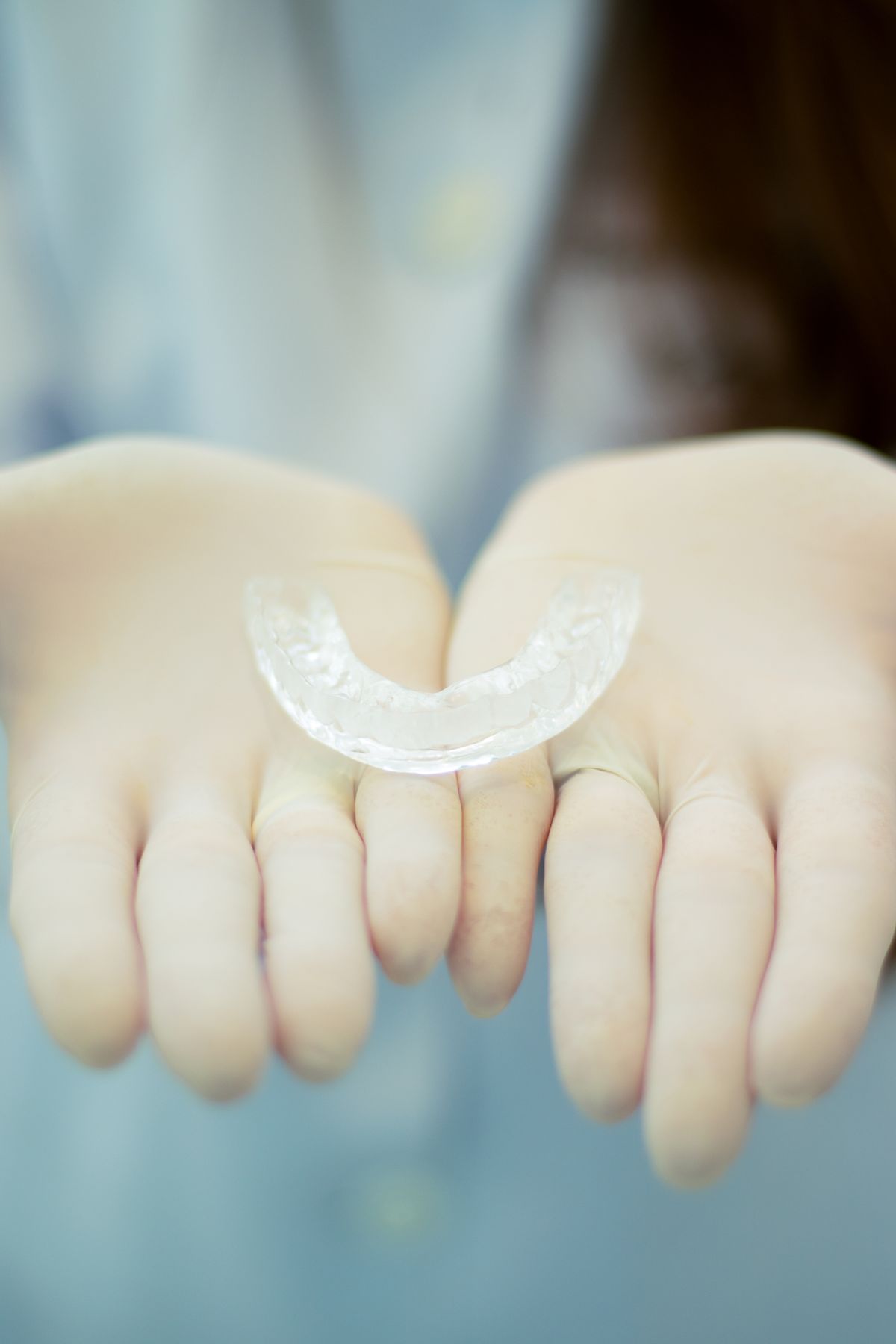 Gloved hands holding a clear retainer